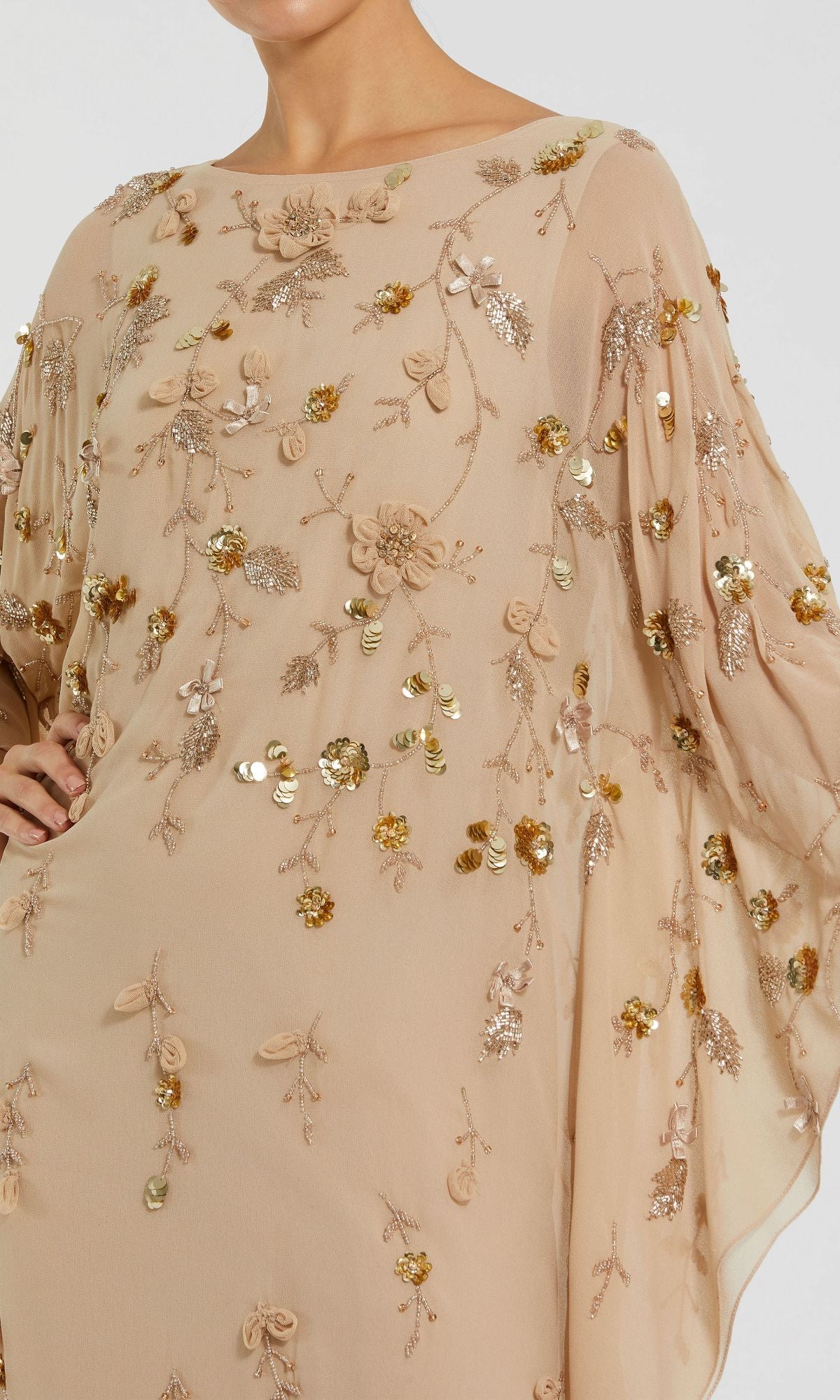 A person wearing the Mac Duggal 9242 Trapeze Embellished Formal Gown—a light beige sheer dress with gold and beige floral embroidery, sequins, and beaded embellishments.